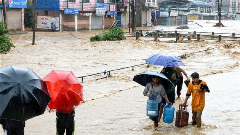 Nepali residents walk through floodwaters carrying items like plastic bottles and gas bottles after the Balkhu River overflowed following monsoon rains at the Kalanki area of Kathmandu on July 12, 2019. (Photo by AFP)
