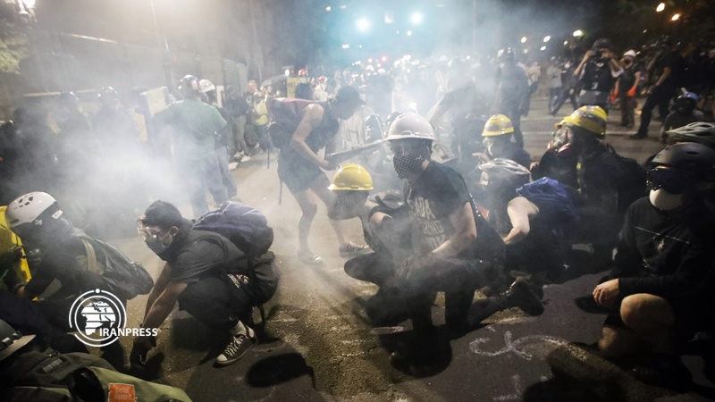 Demonstrators sit and kneel as tear gas fills the air during a protest Sunday in Portland. (Photo: Associated Press)